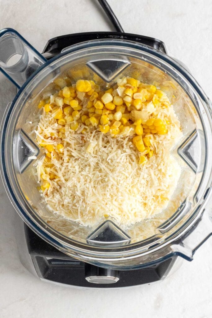 Blender with sautéed onion, garlic, corn kernels, parmesan cheese, lemon juice, and pasta water.