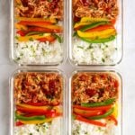 Four glass containers of salsa chicken meal prep bowls.