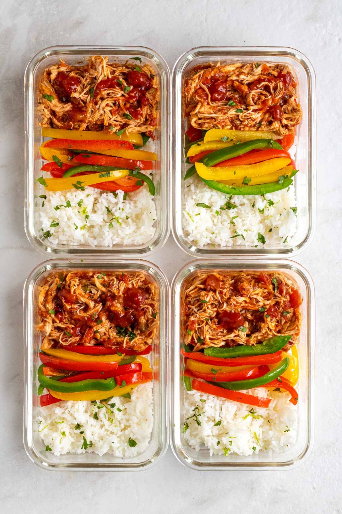 Four glass containers of salsa chicken meal prep bowls.