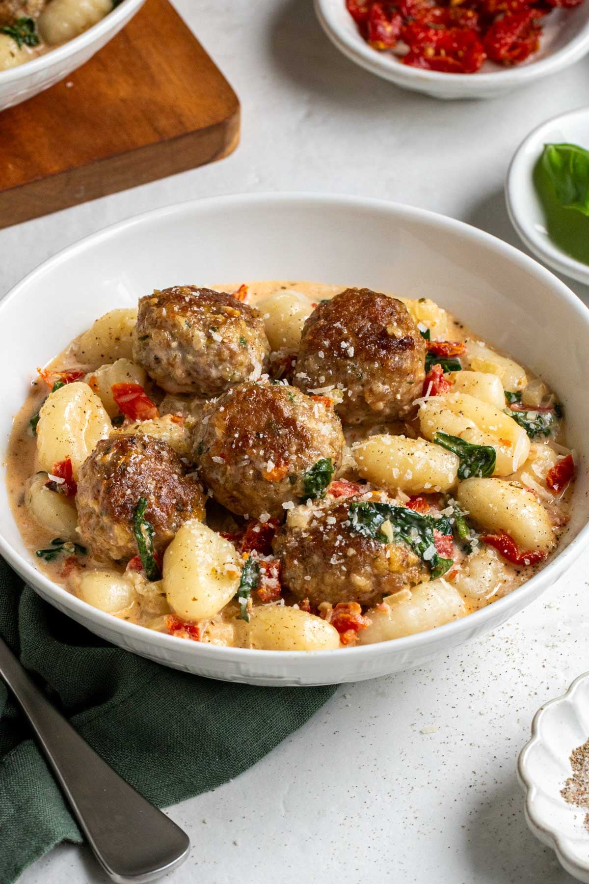 Close up of a bowl of Tuscan chicken meatballs with Gnocchi with freshly grated parmesan cheese on top.