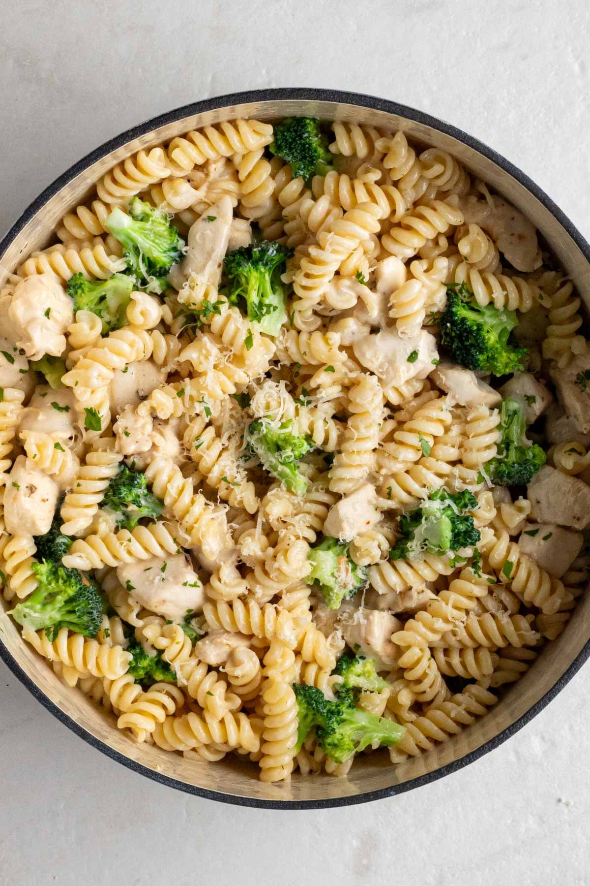 Large pot of chicken and broccoli pasta on a white background.